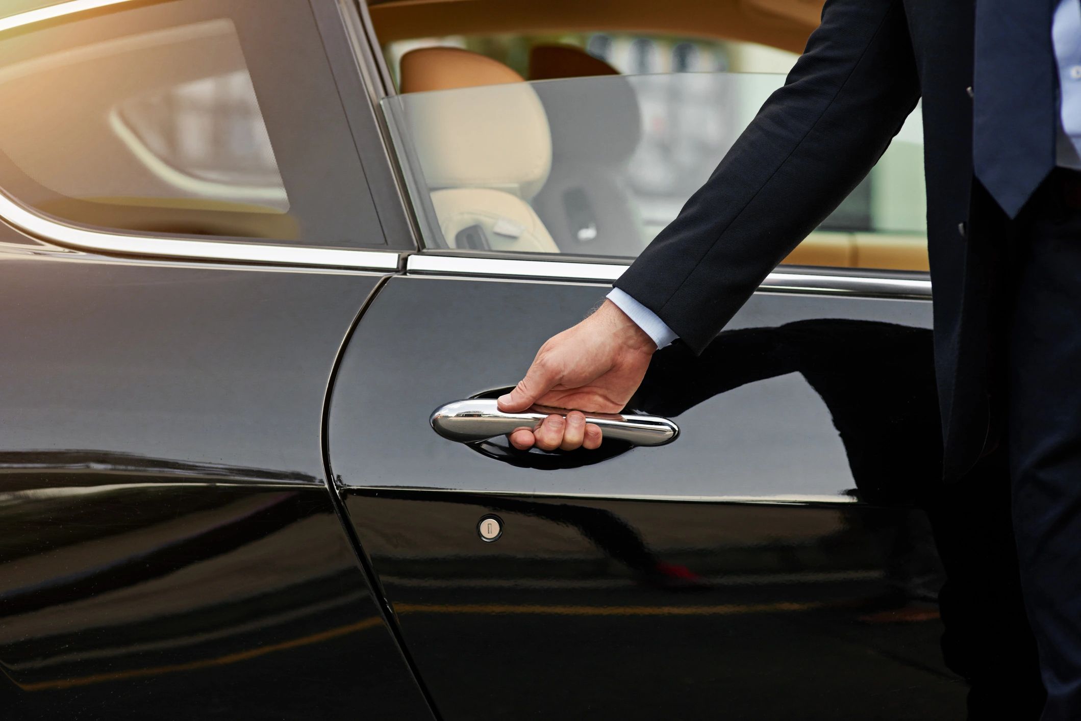 Chauffeur opening luxury car door for executive client